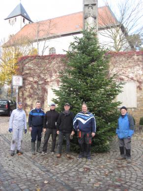 „Volontäre“ stehen vor dem Weihnachtsbaum, zwischen Rathaus und ev. Kirche