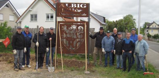 Volontäre neben der neuen Cortenstahltafel am Ortseingang