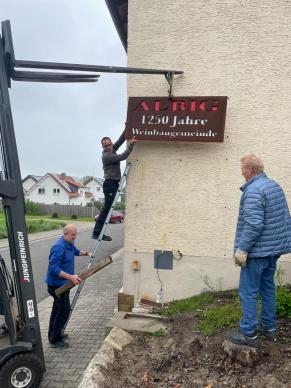 Schild "Albig 1250 Jahre Weinbaugemeinde" wird montiert