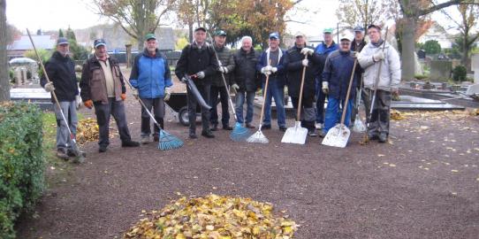Helfer bei der Beseitigung des Laubes auf dem Friedhof