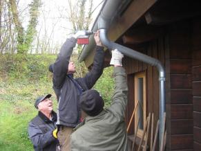 Volontäre reparieren die Dachrinne des Bürgertreffs