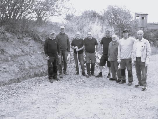 Eine Gruppe von Volontären vor der Sanierungsbedürftigen Trockenmauer