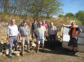 Eine Gruppe von Volontären vor der Bruchsteinmauer