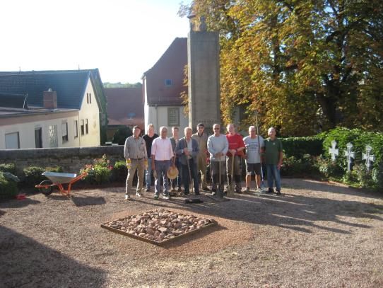 DIe Gruppe der Volontäre stehen auf dem neugestalteten Platz vor dem Ehrenmal