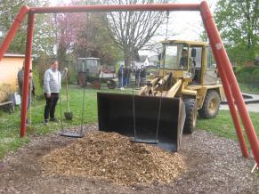 Hackschnitzel werden als Fallschutz unter der Schaukel verteilt